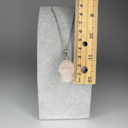 A 3 cm skull pendant carved from various minerals, symbolizing wisdom and transformation, with a stainless steel chain.