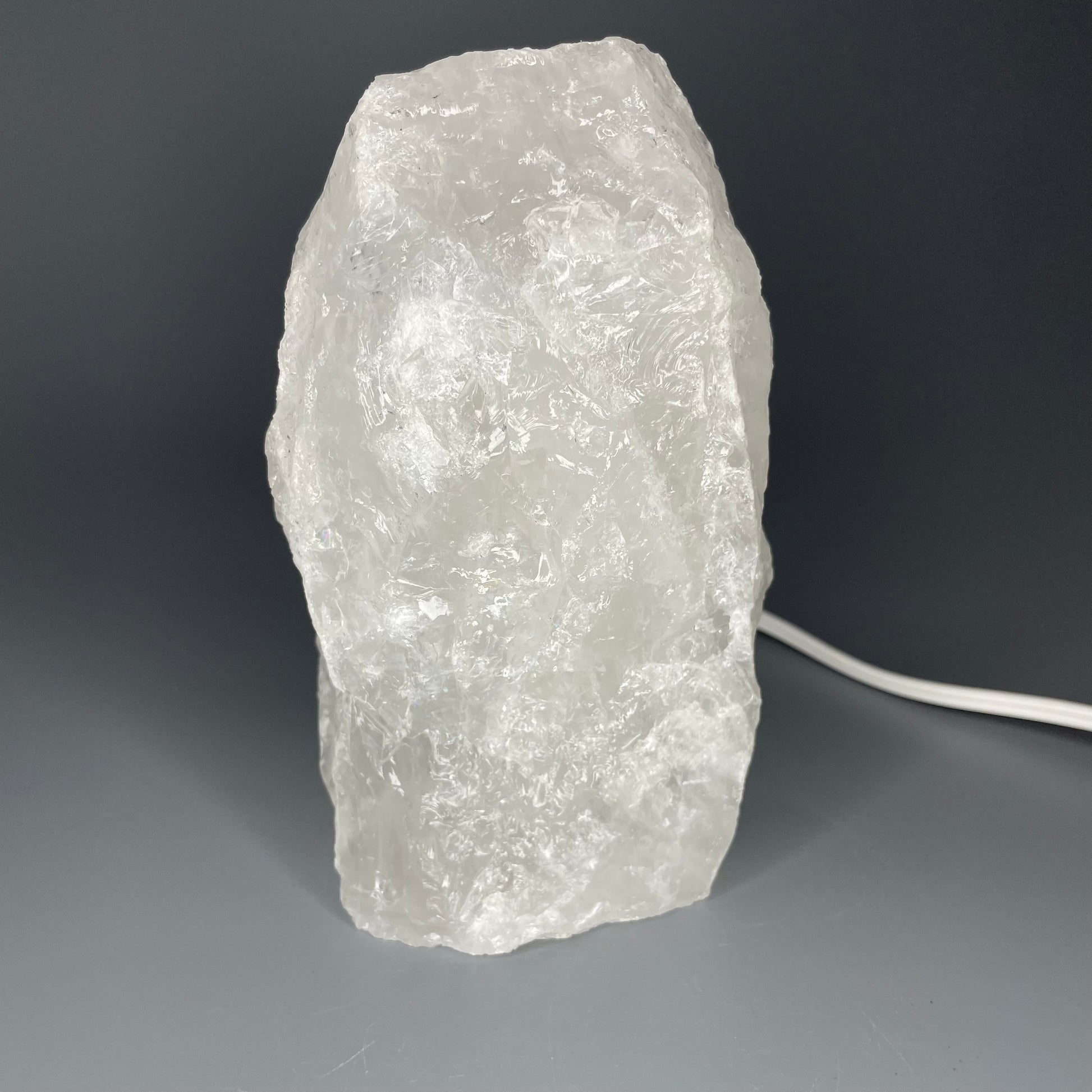 A glowing Clear Quartz Mineral Lamp with a bright, translucent appearance.