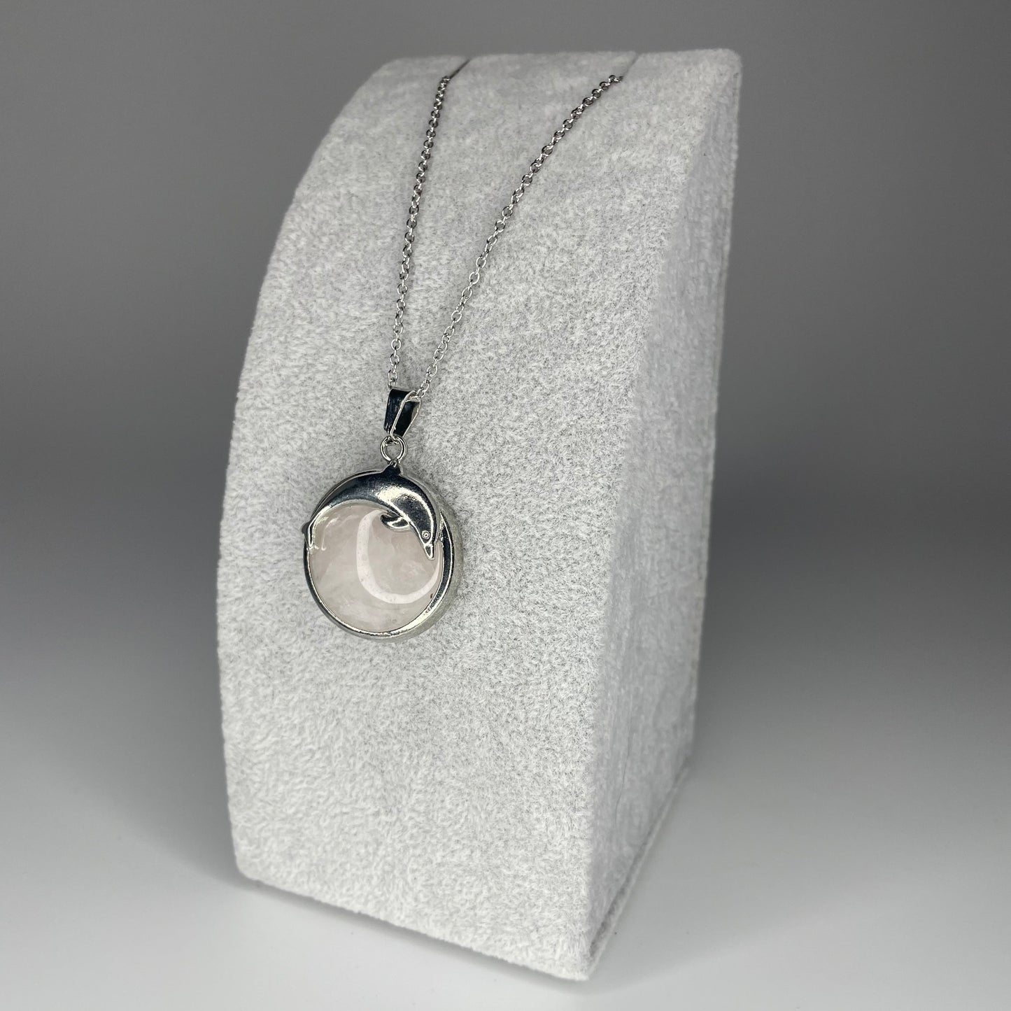 A 3 cm cabochon pendant featuring a dolphin design on a polished stone, available in various minerals, with a stainless steel chain.