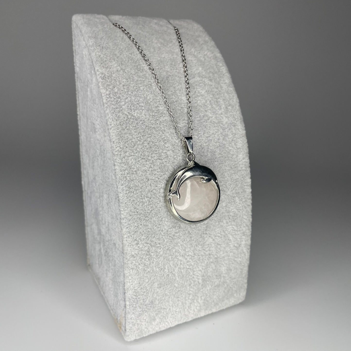 A 3 cm cabochon pendant featuring a dolphin design on a polished stone, available in various minerals, with a stainless steel chain.