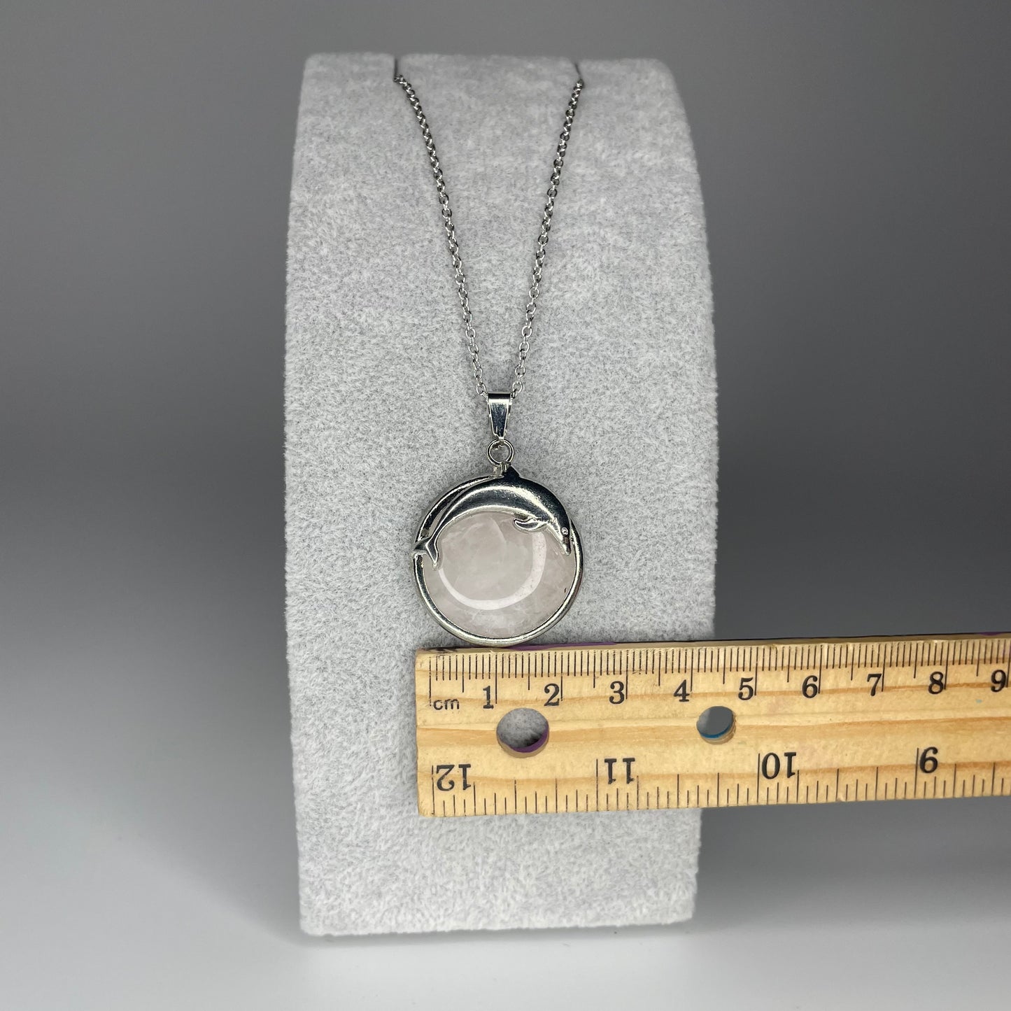 A 3 cm cabochon pendant featuring a dolphin design on a polished stone, available in various minerals, with a stainless steel chain.