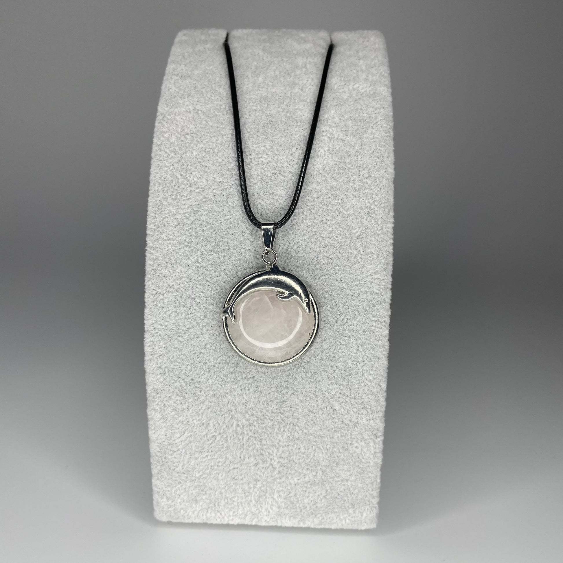 A 3 cm cabochon pendant featuring a dolphin design on a polished stone, available in various minerals, with a black nylon necklace.