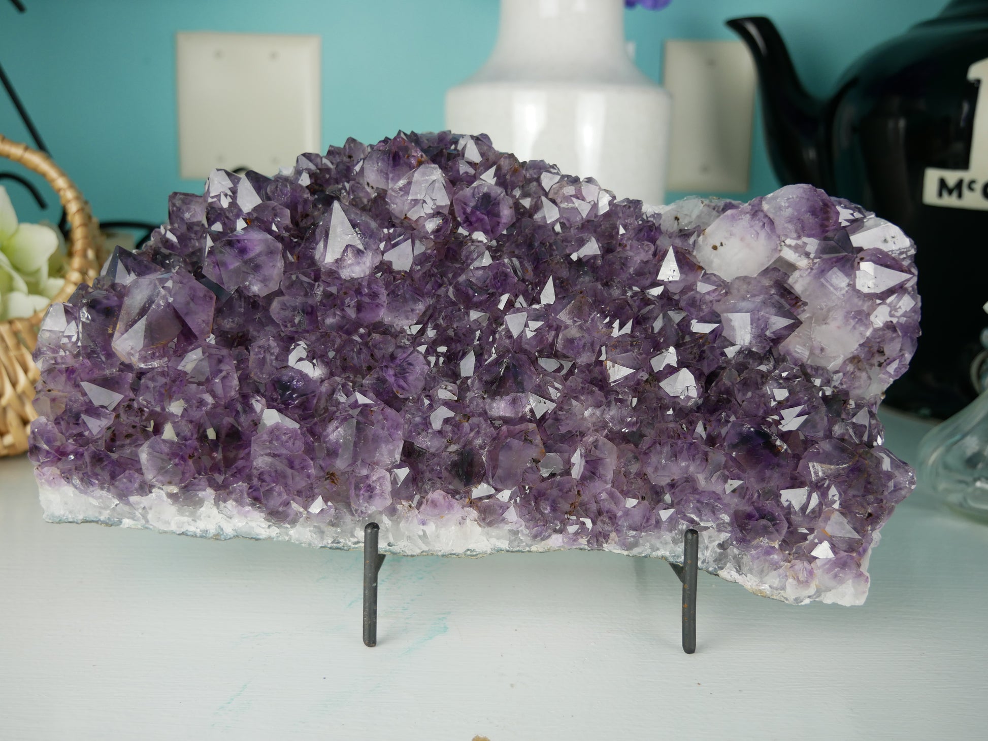 Close-up photo of a stunning amethyst cluster center piece, weighing 112.2 ounces. The cluster showcases a mesmerizing array of deep purple crystals, sparkling under light. Its intricate formations create a captivating display, making it a striking addition to any collection or decor.