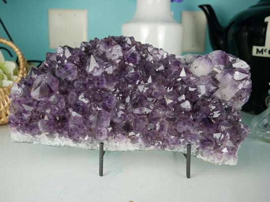 Close-up photo of a stunning amethyst cluster center piece, weighing 112.2 ounces. The cluster showcases a mesmerizing array of deep purple crystals, sparkling under light. Its intricate formations create a captivating display, making it a striking addition to any collection or decor.