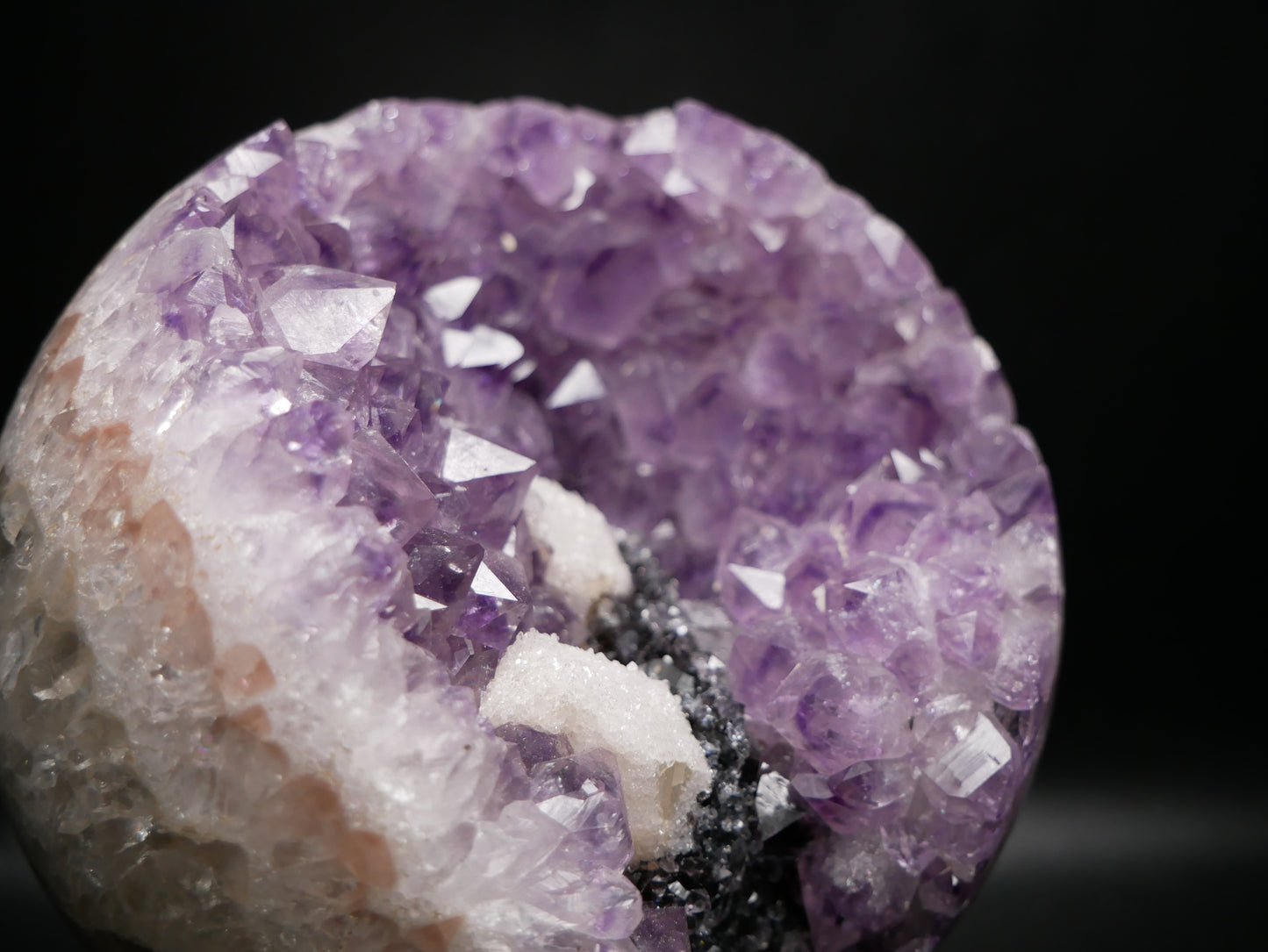 Large amethyst sphere with internal quartz druze on a black background.