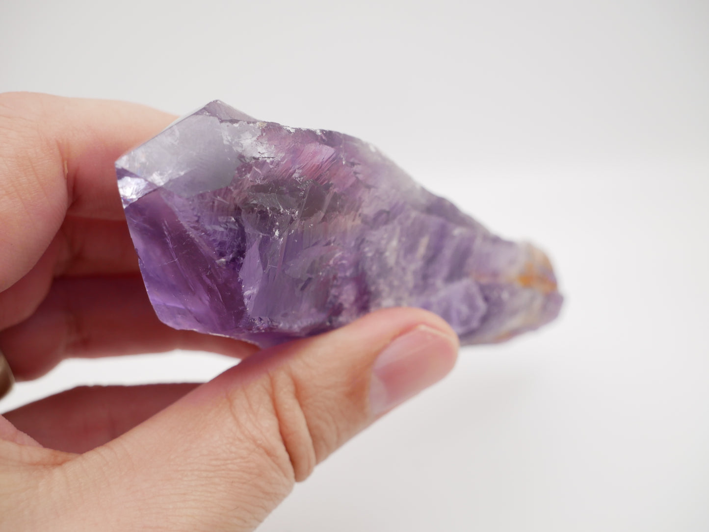 Close-up photo of a stunning 6 oz Brazilian Amethyst Root, measuring 5.25 inches in length. The crystal exhibits vibrant purple hues with natural variations, showcasing its unique beauty and intricate textures.