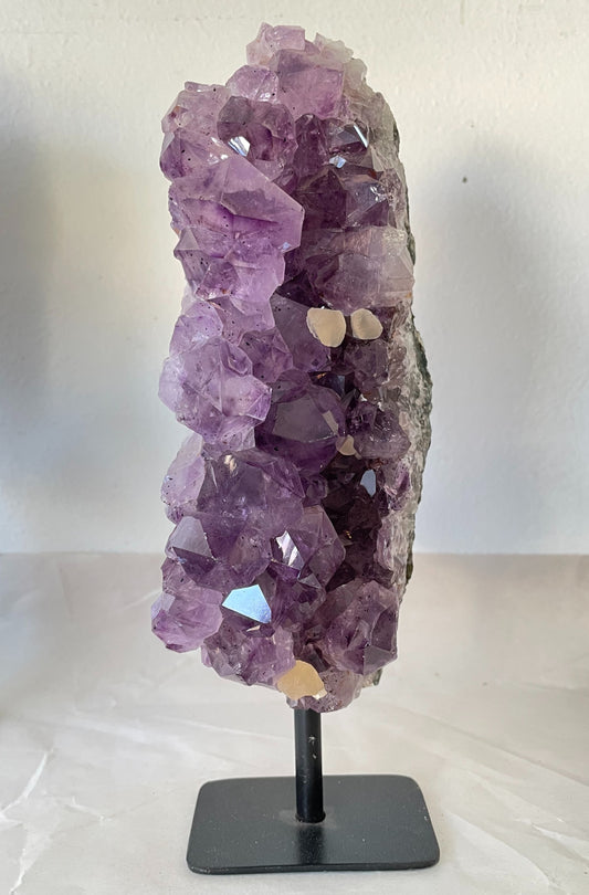 Photograph of a stunning 40-ounce amethyst specimen with calcite accents, displayed on a stand. The vibrant purple hues of the amethyst crystals contrast beautifully with the delicate white calcite formations, creating a captivating natural artwork.