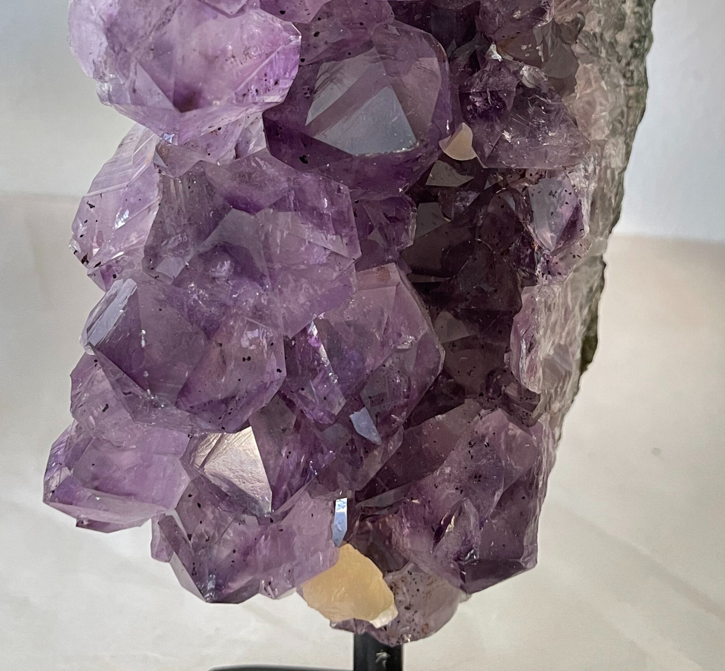 Photograph of a stunning 40-ounce amethyst specimen with calcite accents, displayed on a stand. The vibrant purple hues of the amethyst crystals contrast beautifully with the delicate white calcite formations, creating a captivating natural artwork.