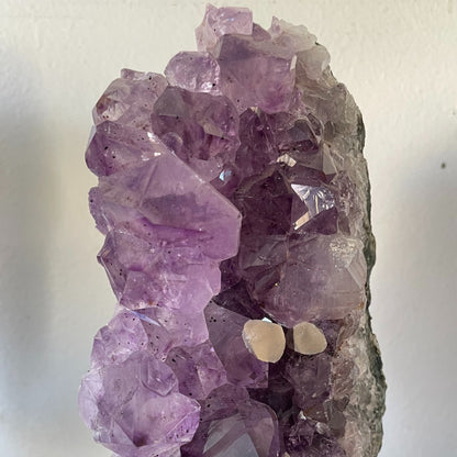 Photograph of a stunning 40-ounce amethyst specimen with calcite accents, displayed on a stand. The vibrant purple hues of the amethyst crystals contrast beautifully with the delicate white calcite formations, creating a captivating natural artwork.