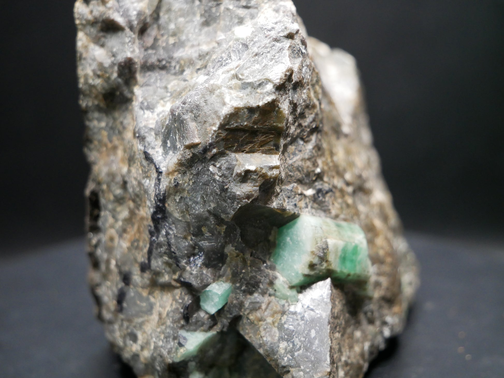 A large emerald in a matrix with distinctive emeralds protruding from the matrix on a black background.