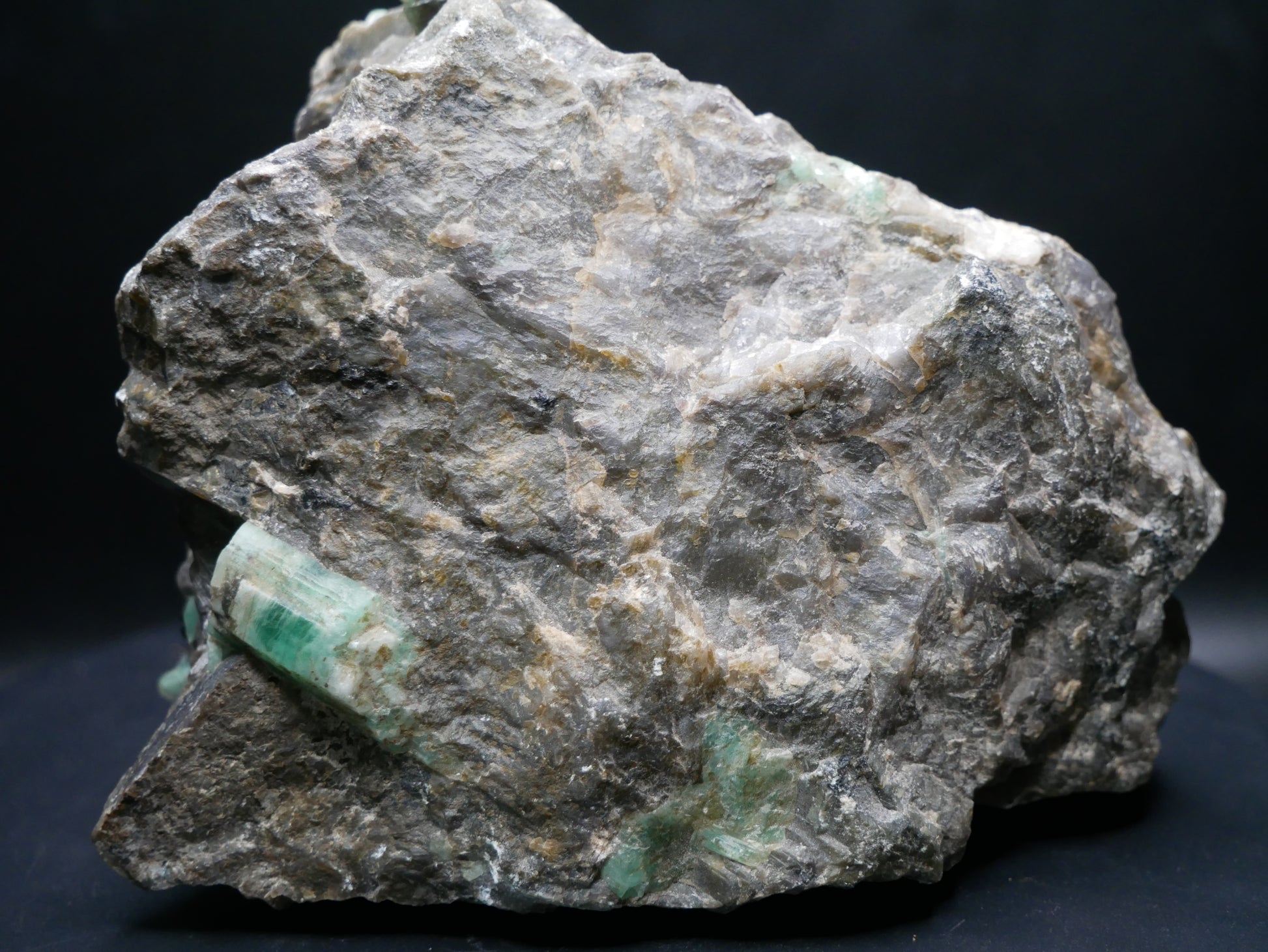 A large emerald in a matrix with distinctive emeralds protruding from the matrix on a black background.