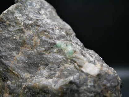 A large emerald in a matrix with distinctive emeralds protruding from the matrix on a black background.