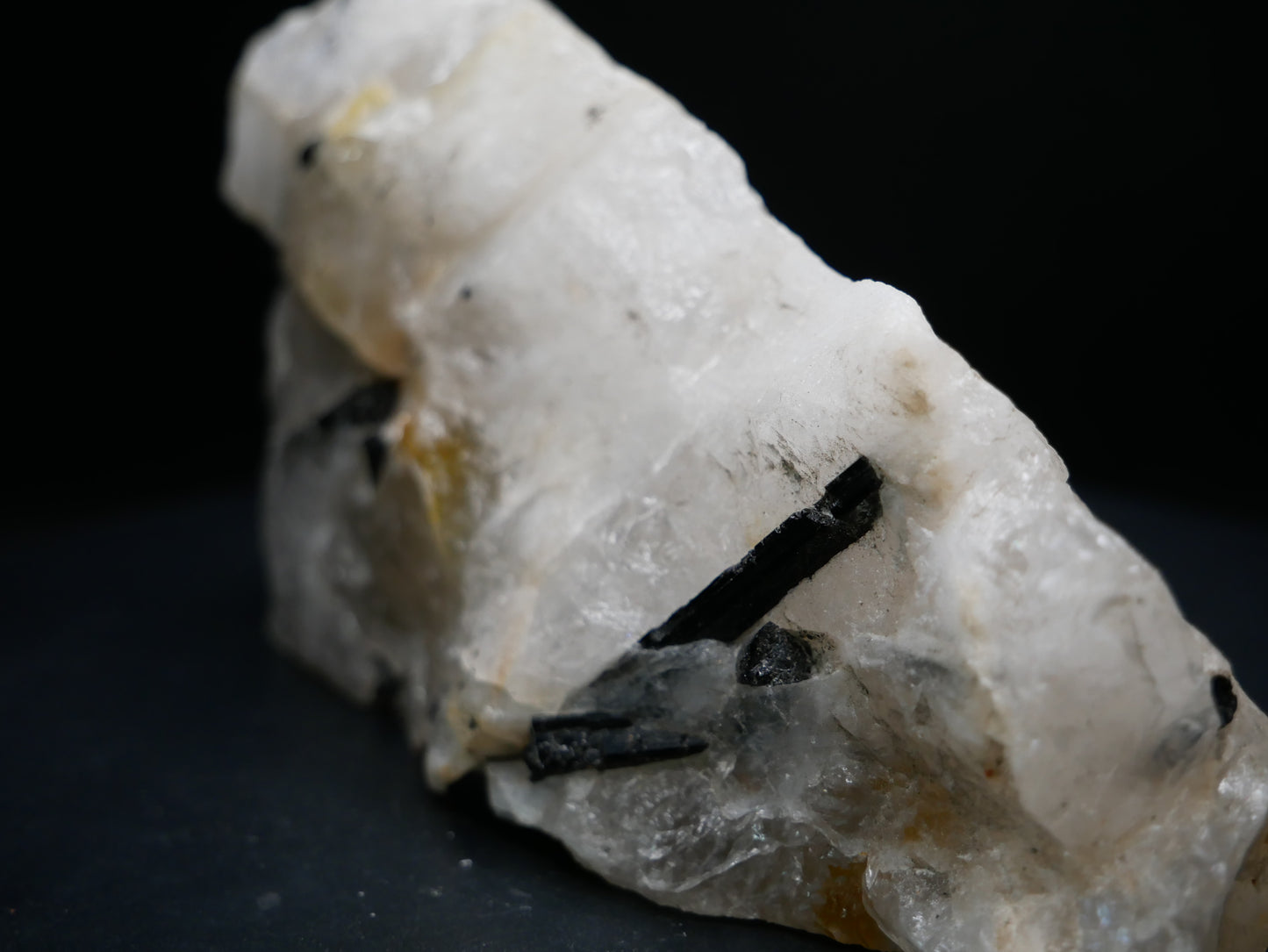 A black tourmaline in a matrix with a distinctive tourmaline crystal protruding from the matrix on a black background.