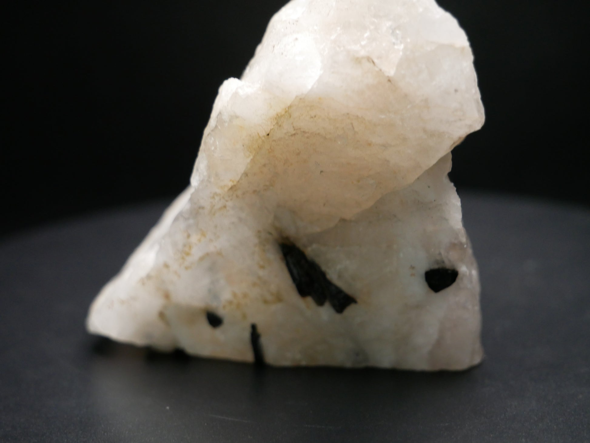 A black tourmaline in a matrix with a distinctive tourmaline crystal protruding from the matrix on a black background.