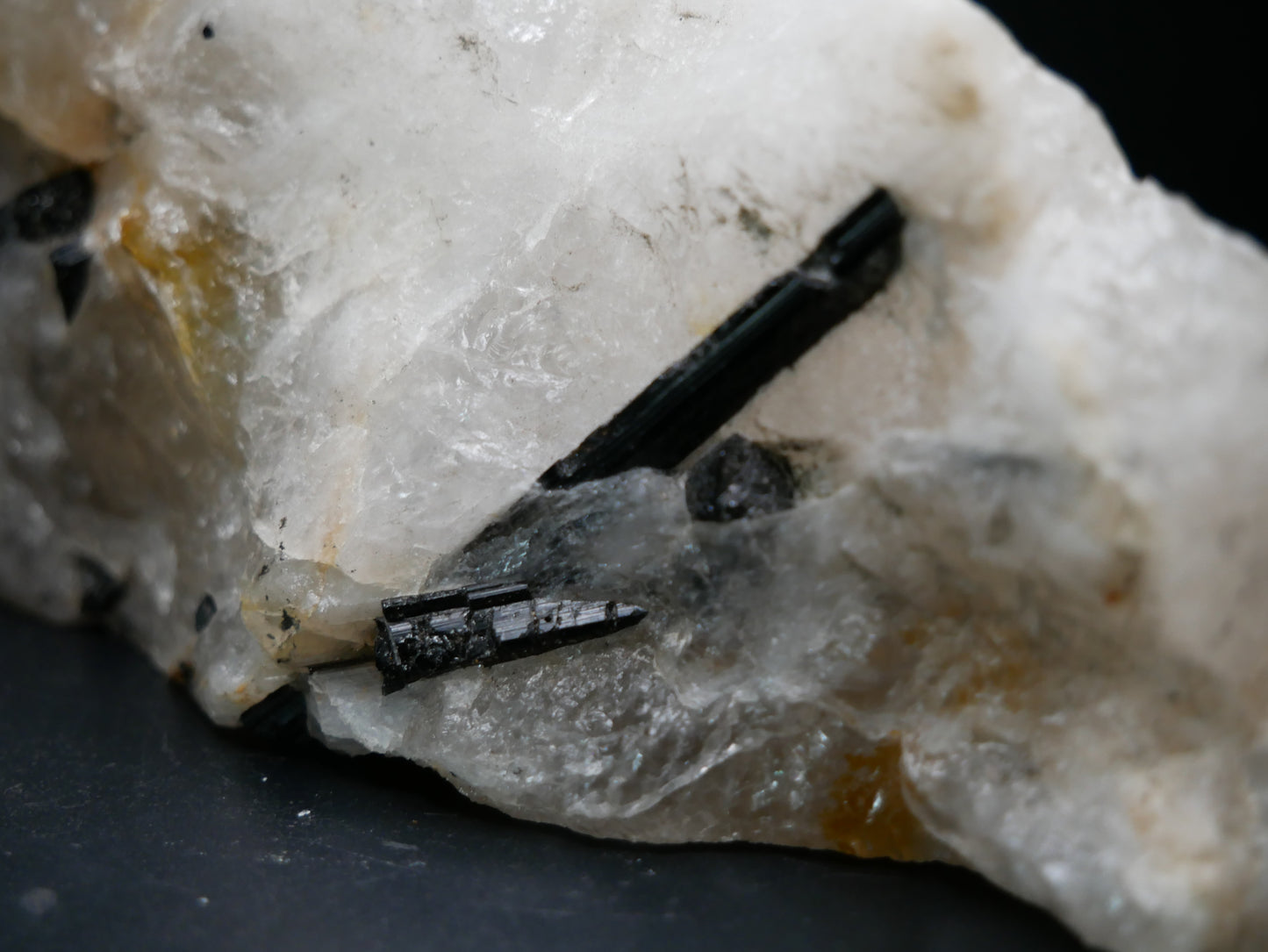 A black tourmaline in a matrix with a distinctive tourmaline crystal protruding from the matrix on a black background.