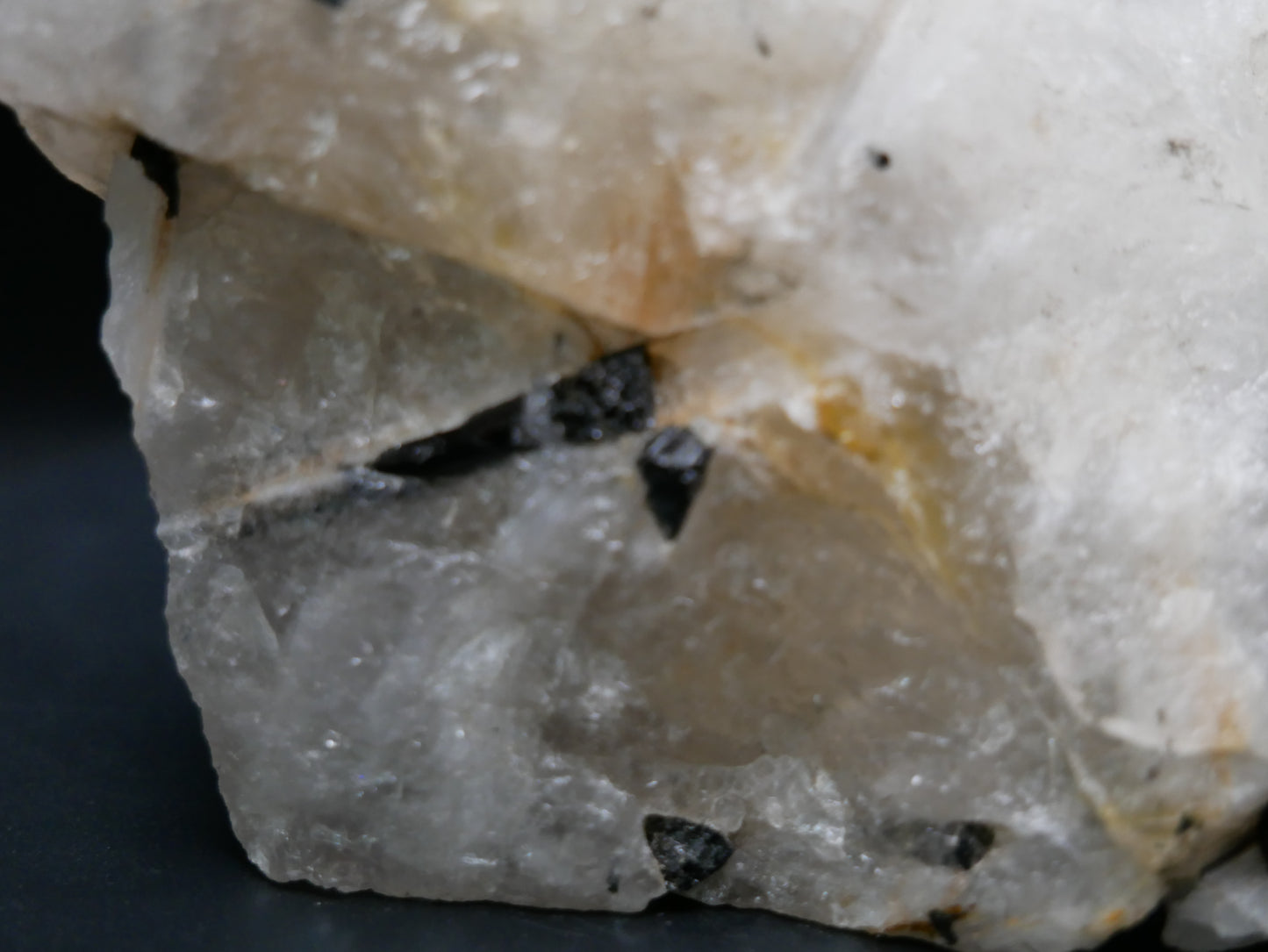 A black tourmaline in a matrix with a distinctive tourmaline crystal protruding from the matrix on a black background.