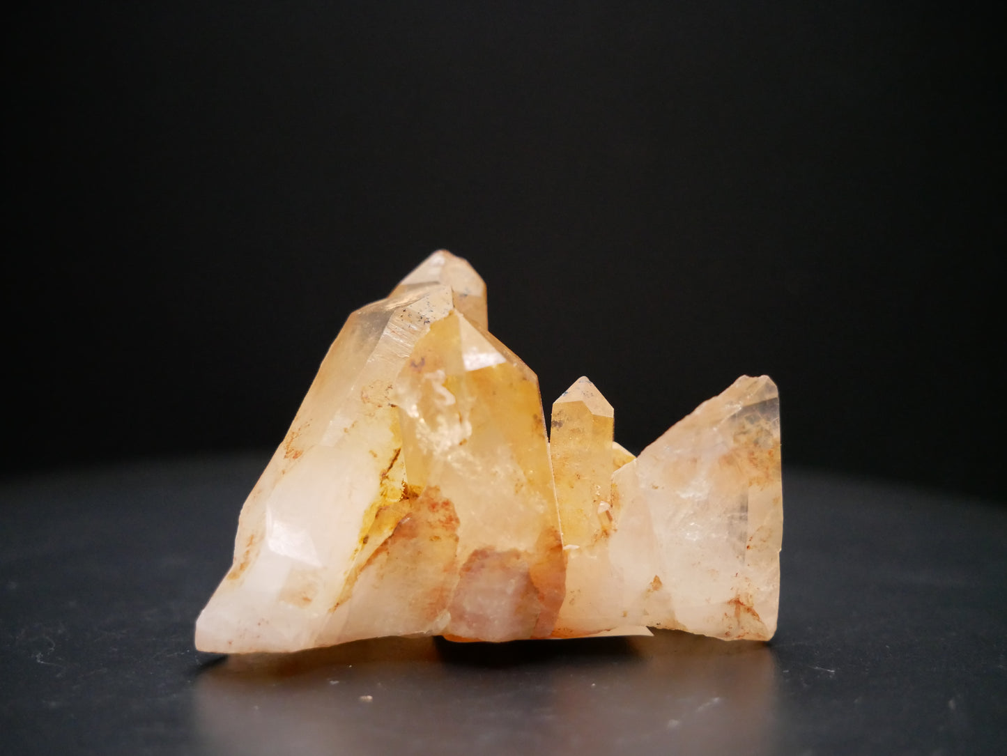 A 56-gram tangerine quartz cluster with distinctive peach-colored crystal formations on a black background.