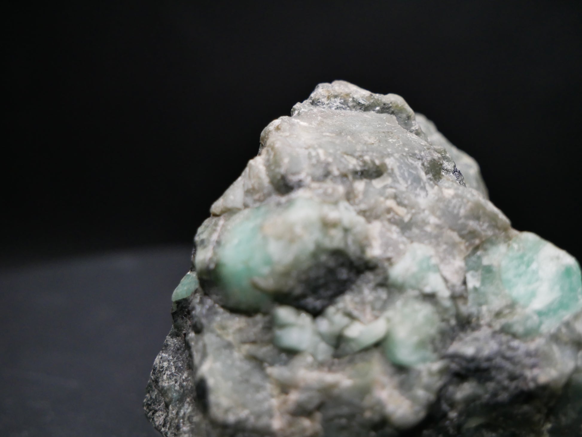 A large emerald in a matrix with distinctive emeralds protruding from the matrix on a black background.