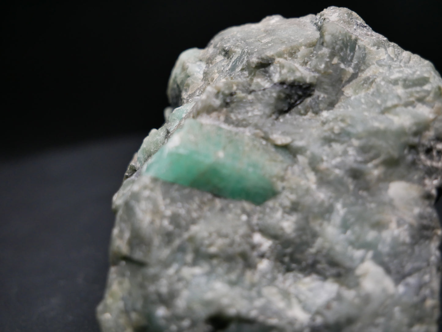 A large emerald in a matrix with distinctive emeralds protruding from the matrix on a black background.