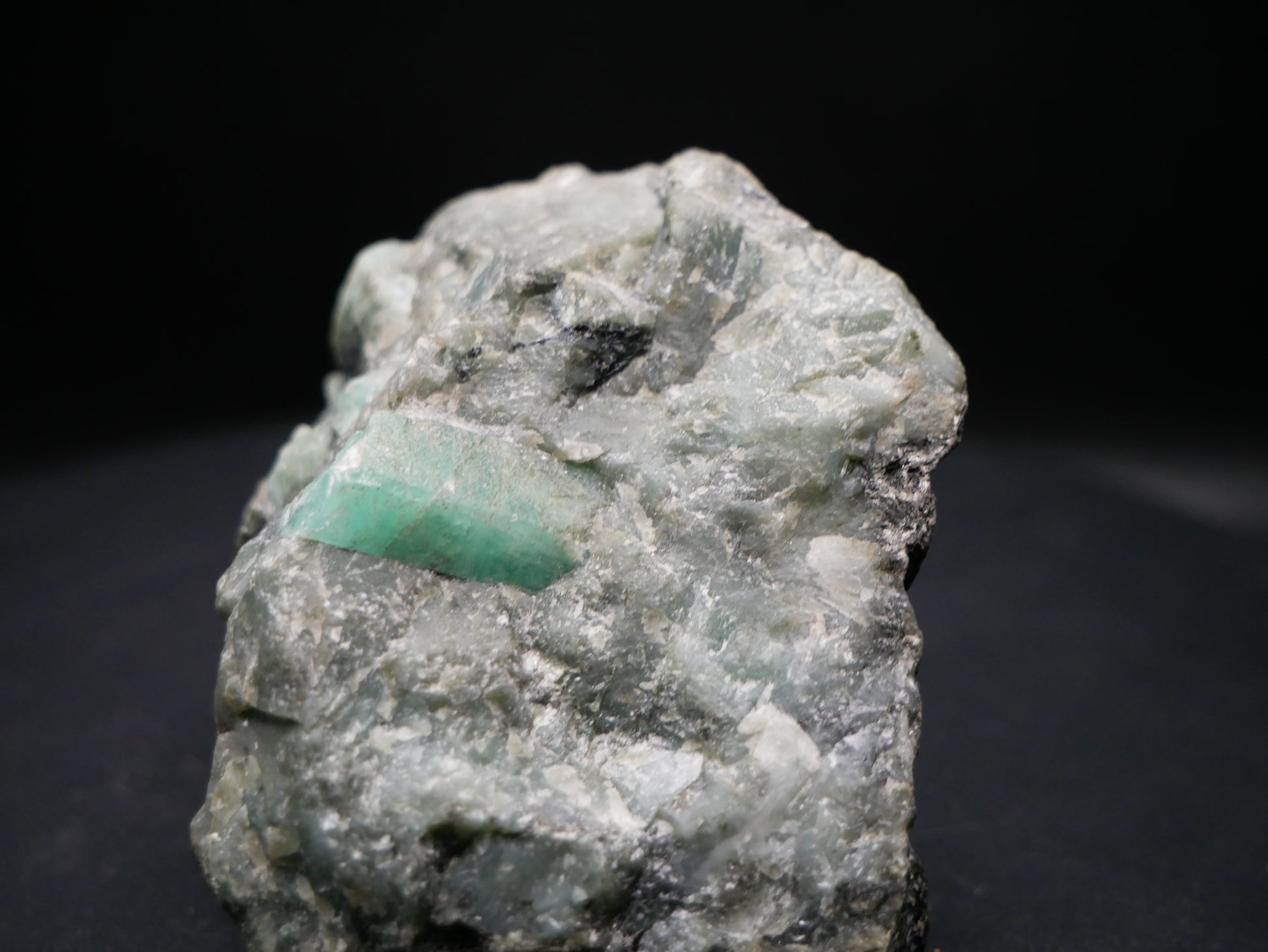 A large emerald in a matrix with distinctive emeralds protruding from the matrix on a black background.