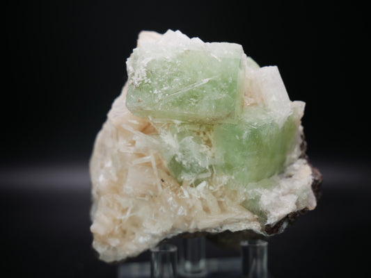 A large, vibrant green Apophyllite crystal formation, adorned with delicate Stilbite clusters, resting on a bed of white Zeolite. The specimen weighs 302.4 grams.