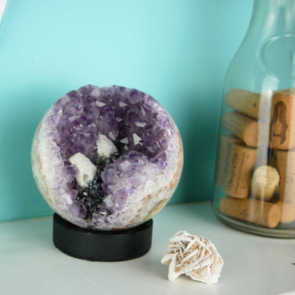 Large amethyst sphere with internal quartz druze on a teal background.