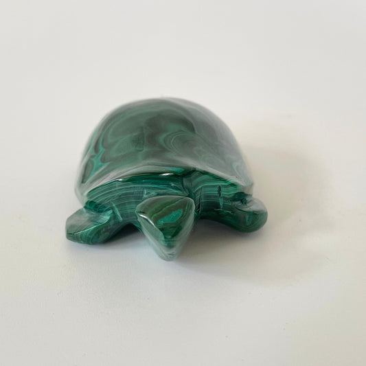 A malachite turtle carving with vibrant green hues and intricate patterns on a white background.