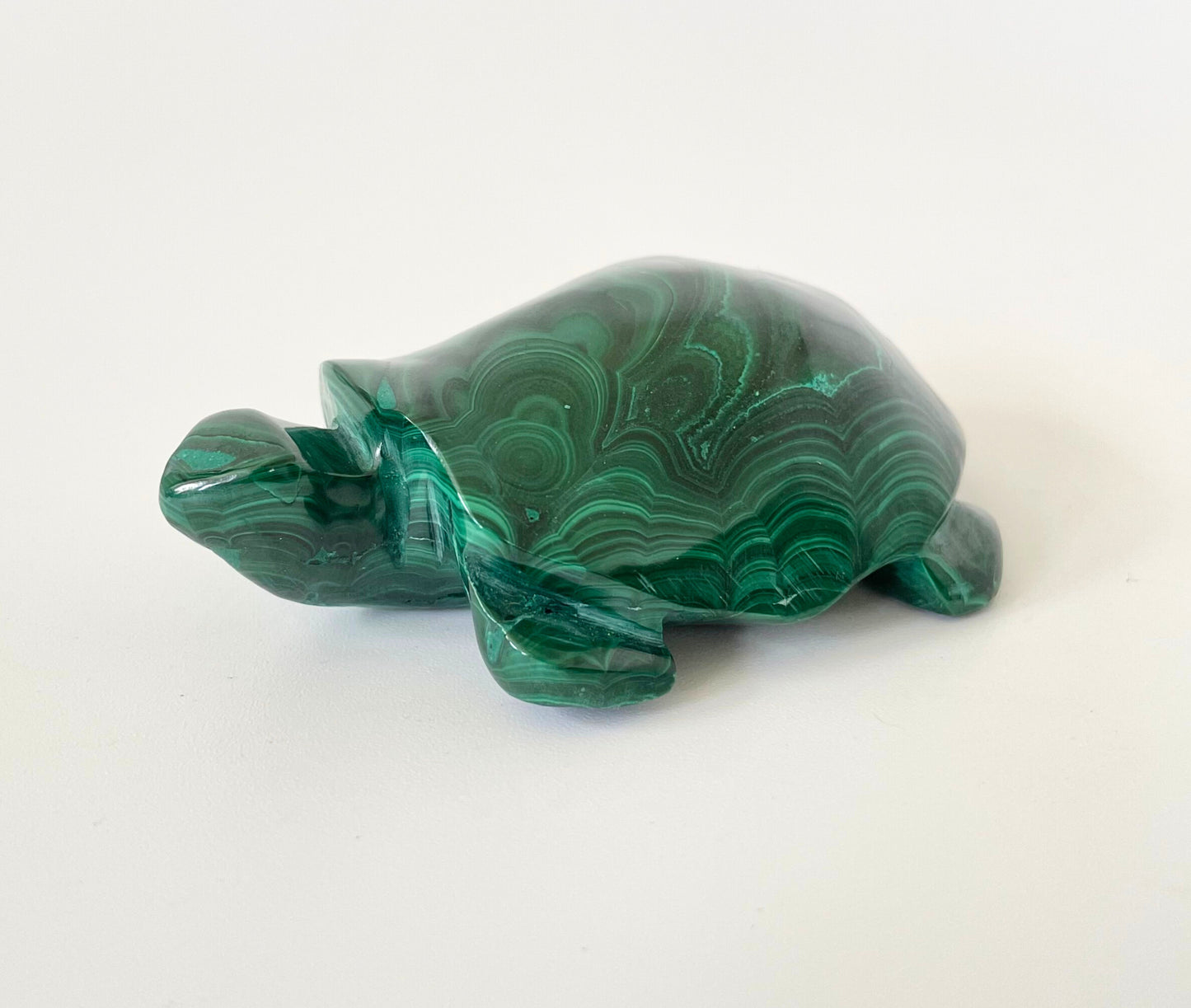 A malachite turtle carving with vibrant green hues and intricate patterns on a white background.