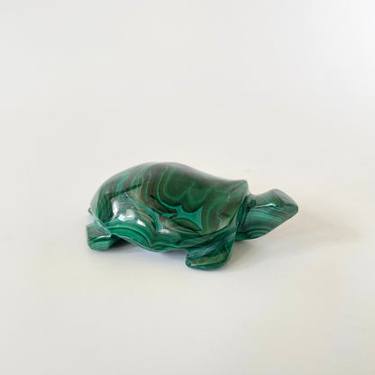 A malachite turtle carving with vibrant green hues and intricate patterns on a white background.