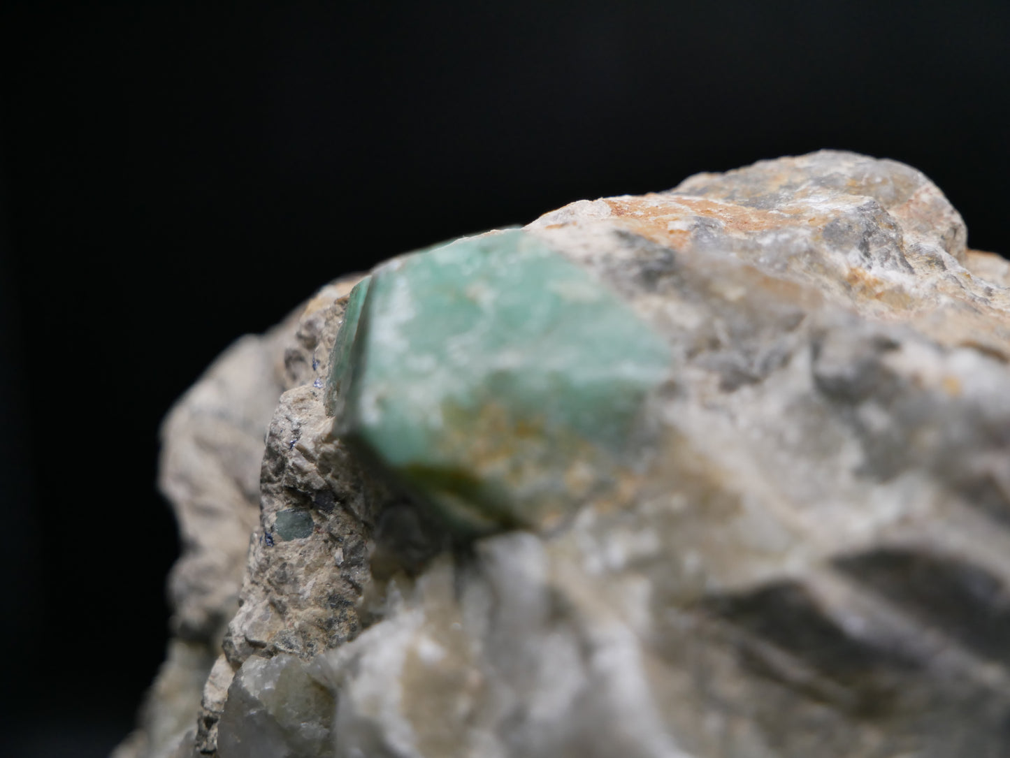 A large emerald in a matrix with distinctive emeralds protruding from the matrix on a black background.