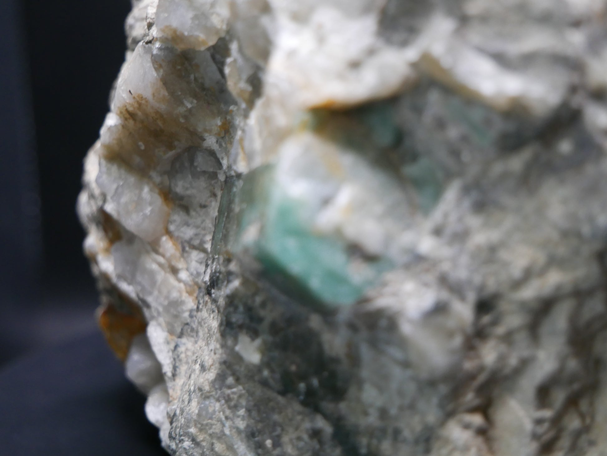 A large emerald in a matrix with distinctive emeralds protruding from the matrix on a black background.