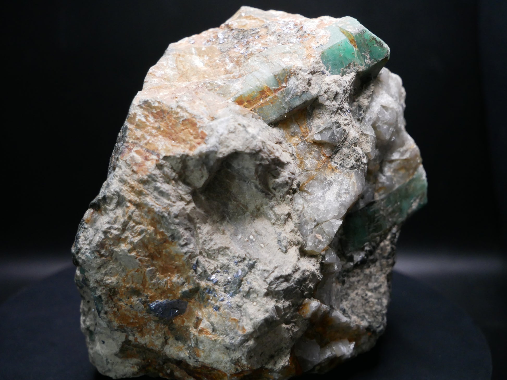 A large emerald in a matrix with distinctive emeralds protruding from the matrix on a black background.