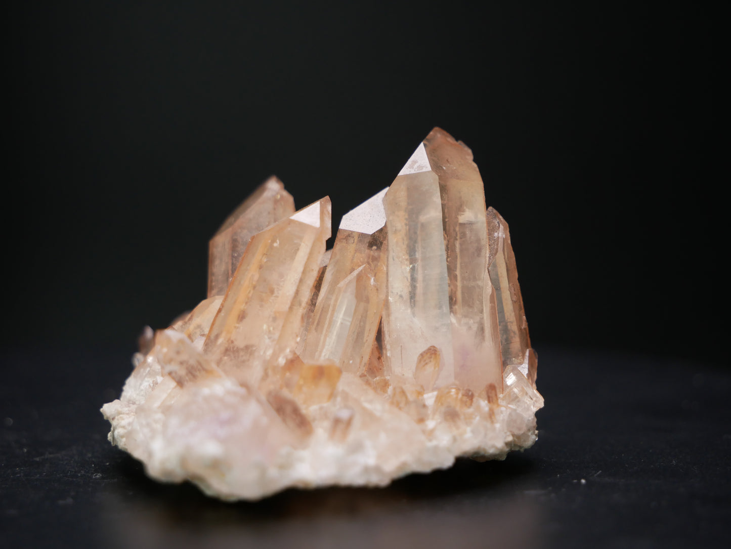 Close-up image of a natural tangerine clear quartz crystal, showcasing its vibrant orange hue and translucent quality, with intricate facets reflecting light.