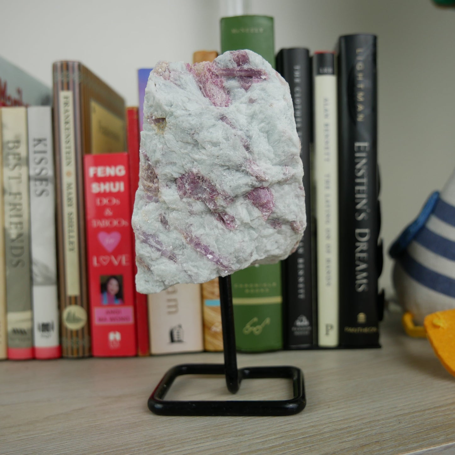 Image of a vibrant pink tourmaline specimen showcased on a stand, highlighting its natural beauty and unique crystalline structure