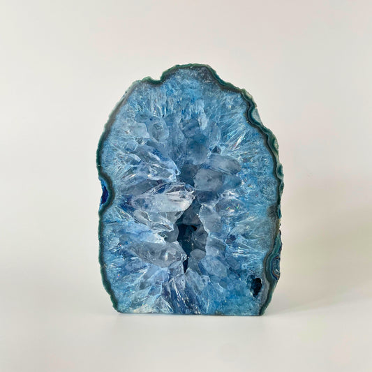 A close-up image of a polished blue agate end with Druze crystals sparkling in the light. The agate displays a smooth, glossy surface with mesmerizing bands of blue hues. The Druze crystals add a beautiful texture and depth to the piece, creating a captivating visual contrast.