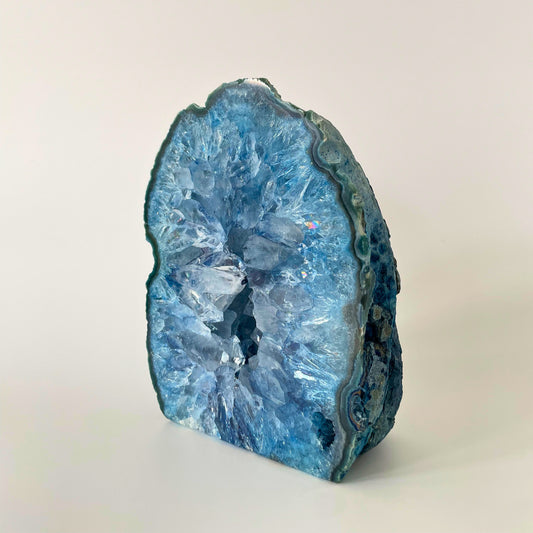 A close-up image of a polished blue agate end with Druze crystals sparkling in the light. The agate displays a smooth, glossy surface with mesmerizing bands of blue hues. The Druze crystals add a beautiful texture and depth to the piece, creating a captivating visual contrast.