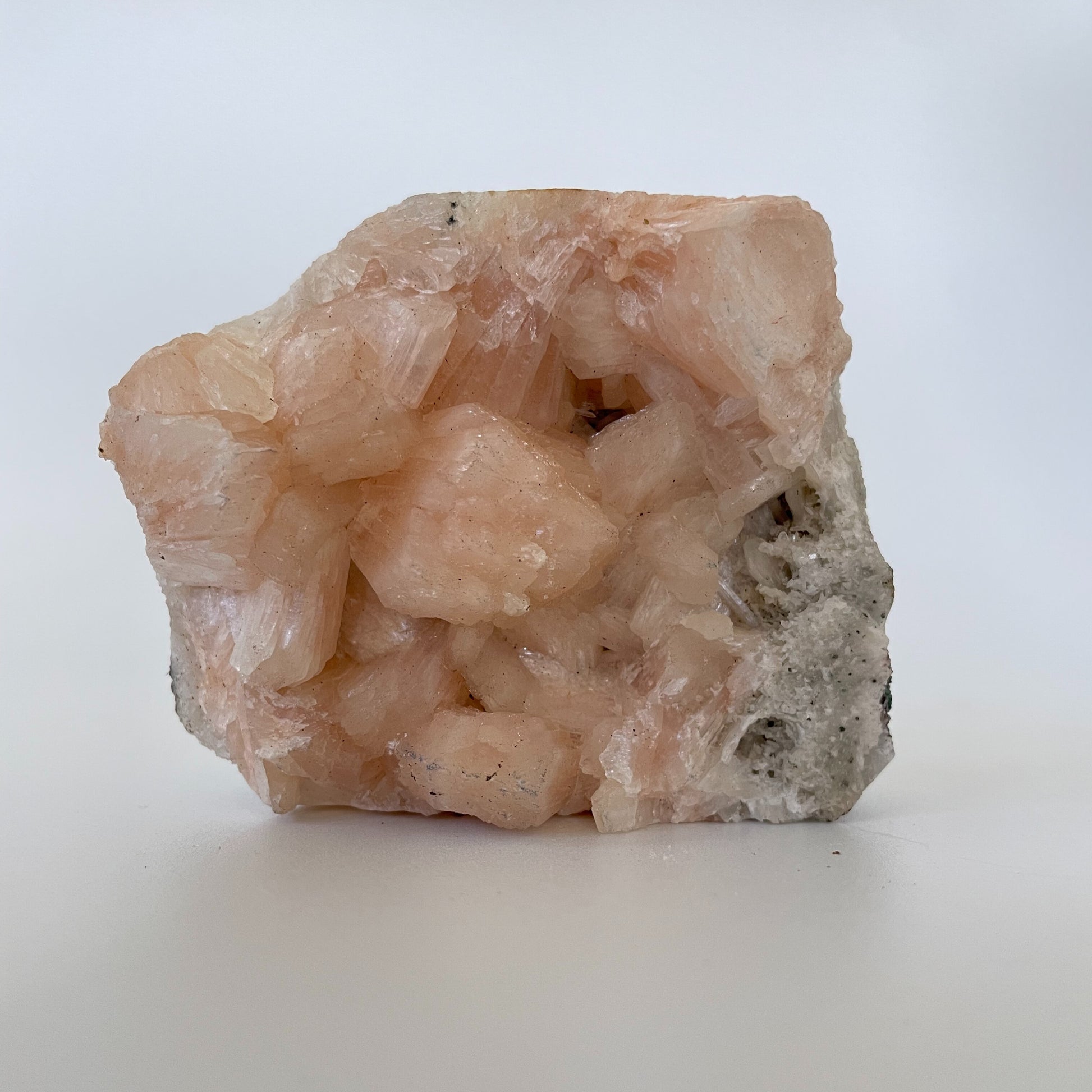 A 3-inch stilbite cluster with distinctive peach-colored crystal formations on a white background.