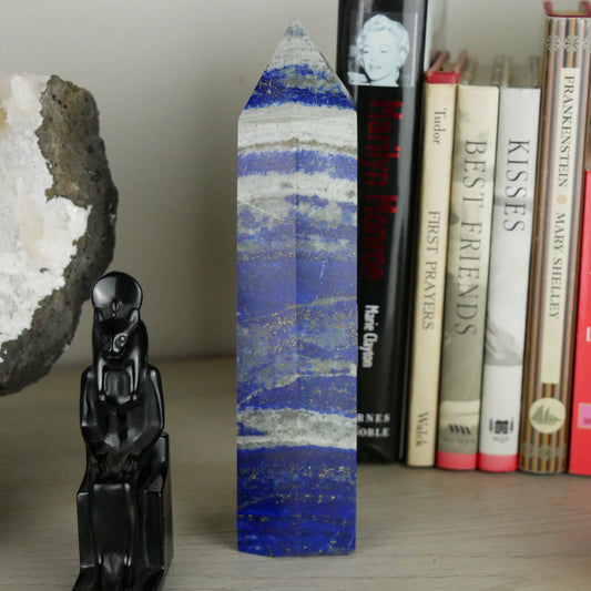 Close-up photo of a 1.43-inch tall Lapis Lazuli tower, showcasing its deep blue hue with golden flecks. The tower stands upright, displaying its polished surface and natural variations in texture.