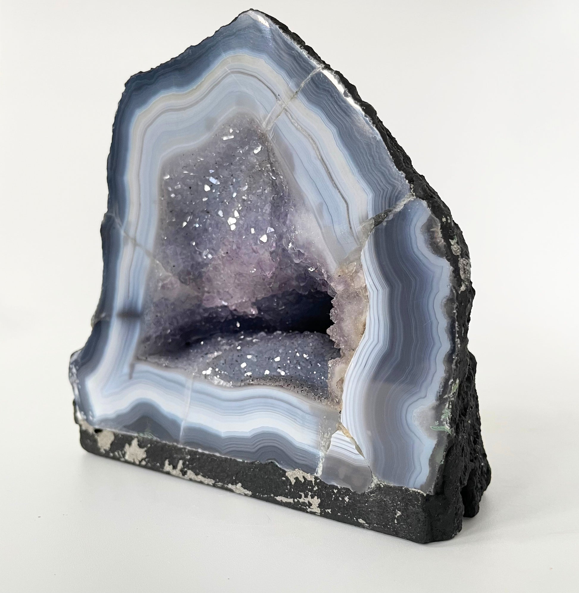 Amethyst cathedral with brilliant hues of deep purple and various sizes of crystal formations on a white background.