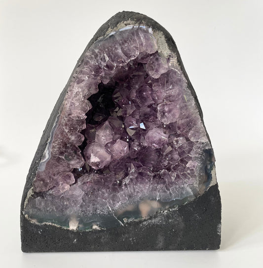 Amethyst cathedral with brilliant hues of deep purple and various sizes of crystal formations on a white background.