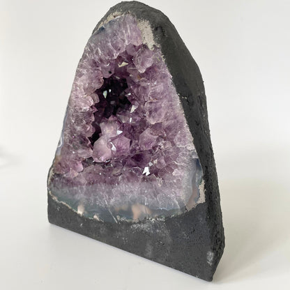 Amethyst cathedral with brilliant hues of deep purple and various sizes of crystal formations on a white background.