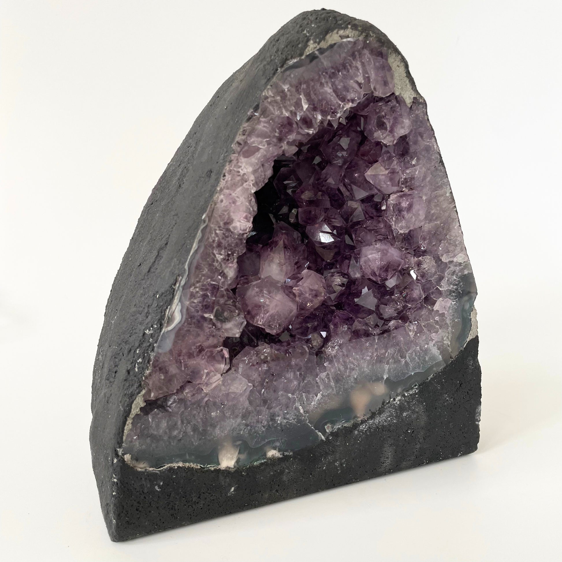 Amethyst cathedral with brilliant hues of deep purple and various sizes of crystal formations on a white background.