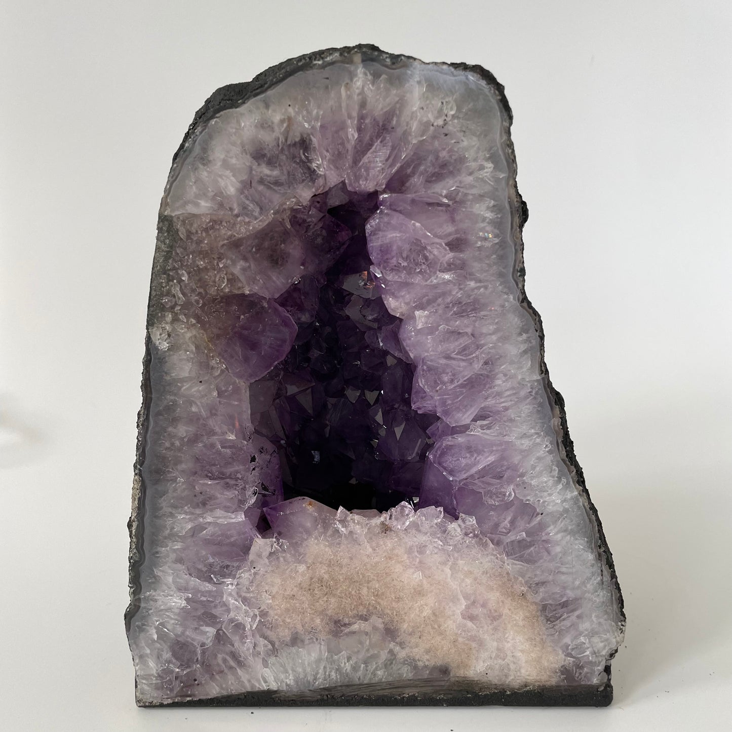 Amethyst cathedral with brilliant hues of deep purple and various sizes of crystal formations on a white background.