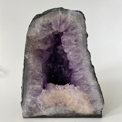 Amethyst cathedral with brilliant hues of deep purple and various sizes of crystal formations on a white background.