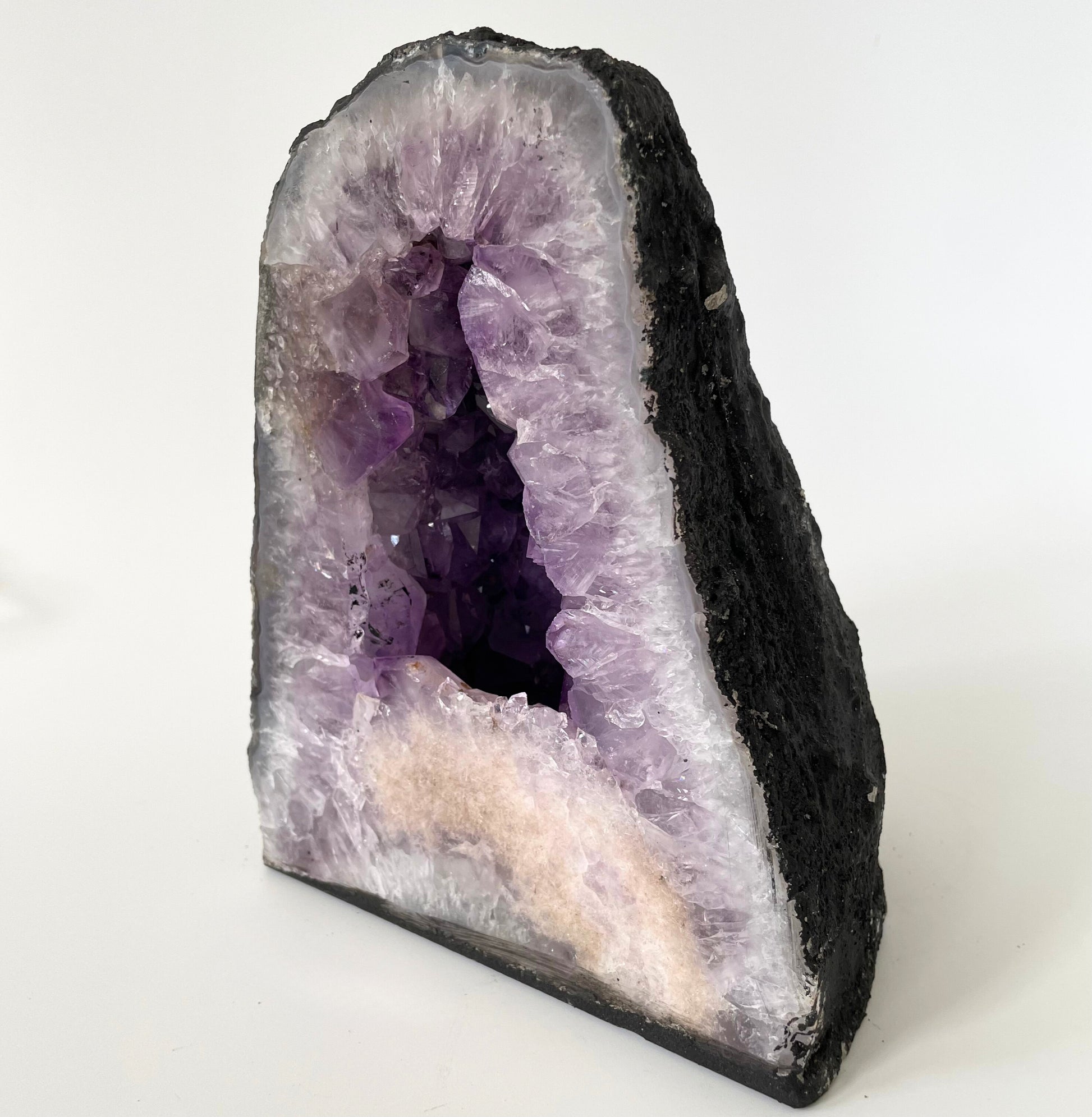 Amethyst cathedral with brilliant hues of deep purple and various sizes of crystal formations on a white background.