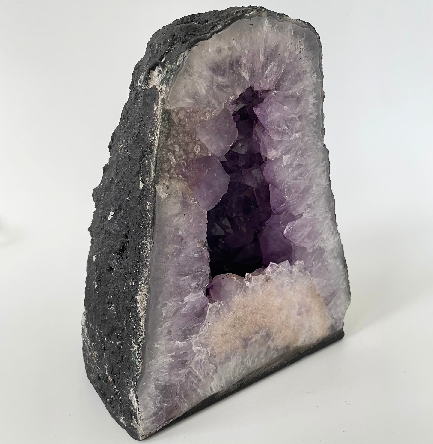 Amethyst cathedral with brilliant hues of deep purple and various sizes of crystal formations on a white background.