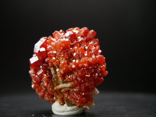 Vanadinite crystal specimen on matrix from Morocco: A cluster of vibrant, hexagonal vanadinite crystals arranged on a rocky matrix, showcasing rich reddish-brown hues.