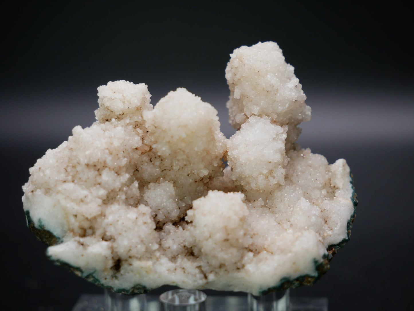 Close-up photo of a cluster of Zeolite Towers sitting on a rocky matrix, weighing 50.4 grams. The Zeolite Towers display a variety of delicate, intricate crystalline structures, while the matrix provides a natural contrast in colors and textures. Light reflects off the surfaces, showcasing the specimen's beauty and uniqueness.