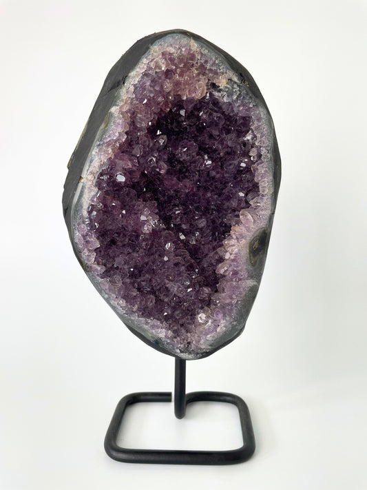 Image of a gleaming amethyst cluster displayed on a stand, showcasing its vibrant purple hues and natural crystal formations.