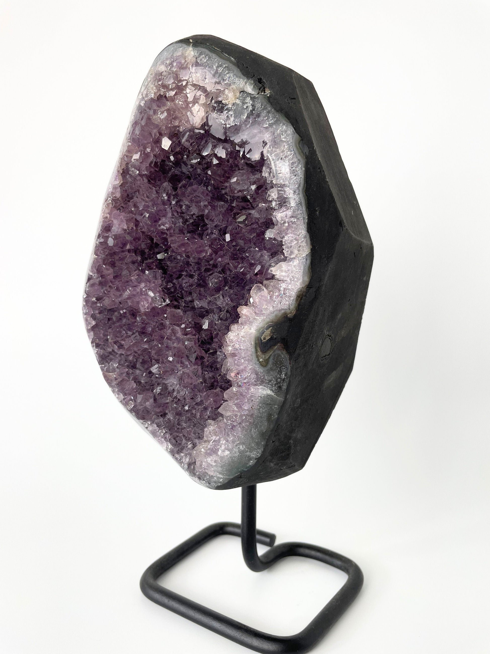 Image of a gleaming amethyst cluster displayed on a stand, showcasing its vibrant purple hues and natural crystal formations.